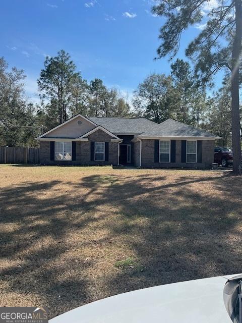 ranch-style house with fence, a front lawn, and brick siding