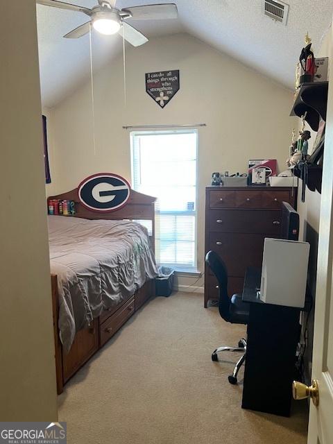 carpeted bedroom featuring visible vents, vaulted ceiling, a textured ceiling, and ceiling fan