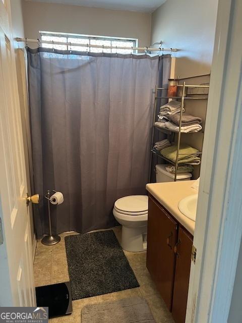 bathroom with toilet, a shower with shower curtain, vanity, and tile patterned floors