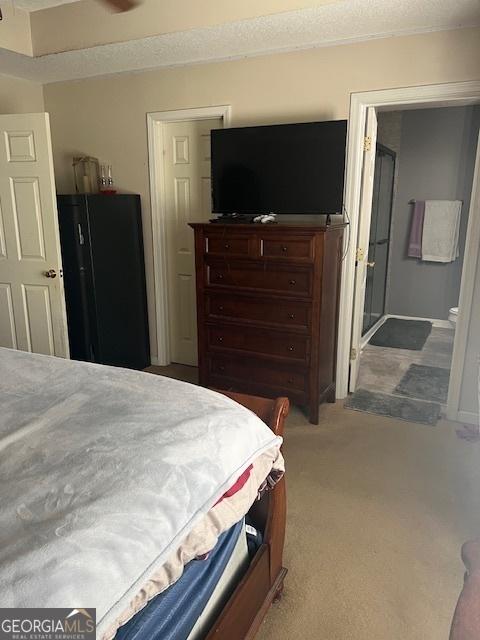 bedroom with carpet flooring and freestanding refrigerator