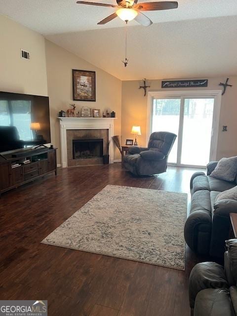 living room with lofted ceiling, visible vents, a tiled fireplace, a textured ceiling, and wood finished floors