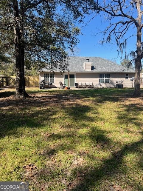 back of property featuring a patio area, a yard, a chimney, and fence