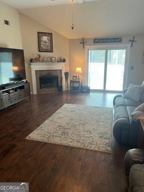 living area featuring a fireplace, visible vents, vaulted ceiling, and wood finished floors