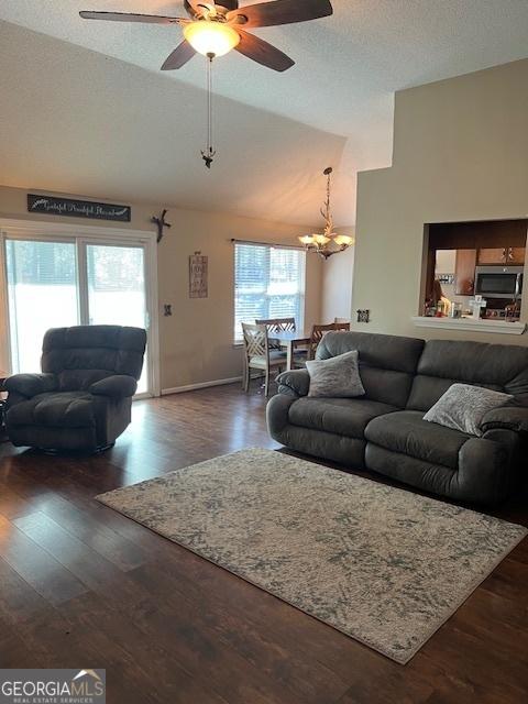 living room featuring lofted ceiling, dark wood-style floors, a textured ceiling, and ceiling fan with notable chandelier