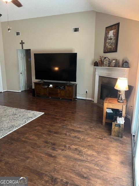 living area featuring ceiling fan, a fireplace, vaulted ceiling, and wood finished floors