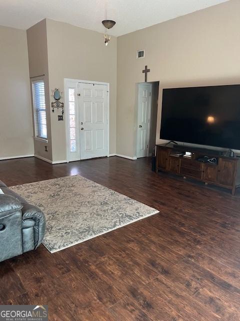 foyer entrance featuring high vaulted ceiling, wood finished floors, visible vents, and baseboards