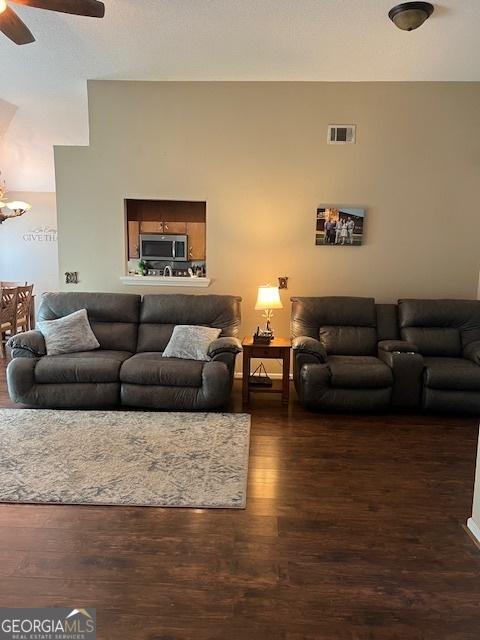 living area featuring visible vents, a textured ceiling, wood finished floors, and a ceiling fan