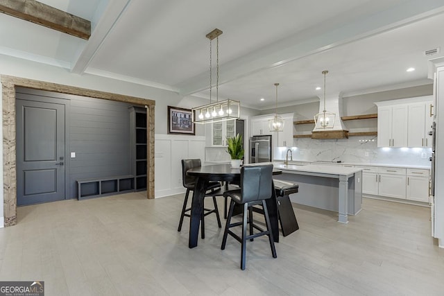 dining area with beam ceiling, a decorative wall, visible vents, and ornamental molding