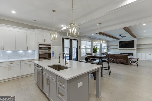 kitchen featuring visible vents, beam ceiling, a sink, appliances with stainless steel finishes, and a fireplace