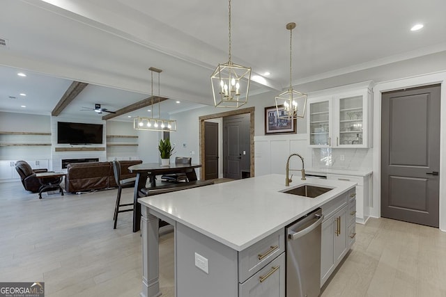 kitchen with beam ceiling, a sink, stainless steel dishwasher, a fireplace, and light countertops