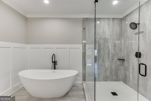 bathroom with a decorative wall, a stall shower, a wainscoted wall, and a freestanding tub