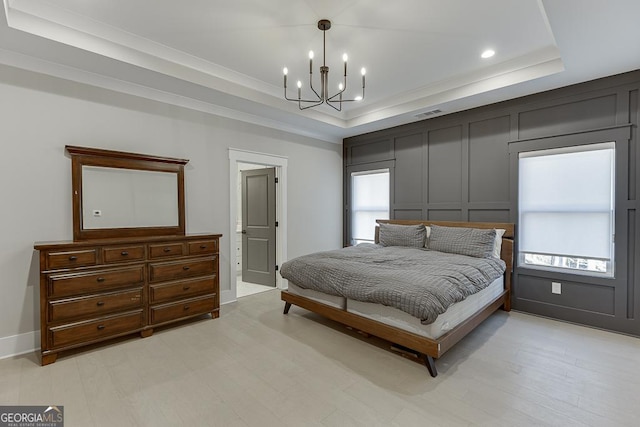 bedroom with a raised ceiling, a decorative wall, a notable chandelier, and visible vents