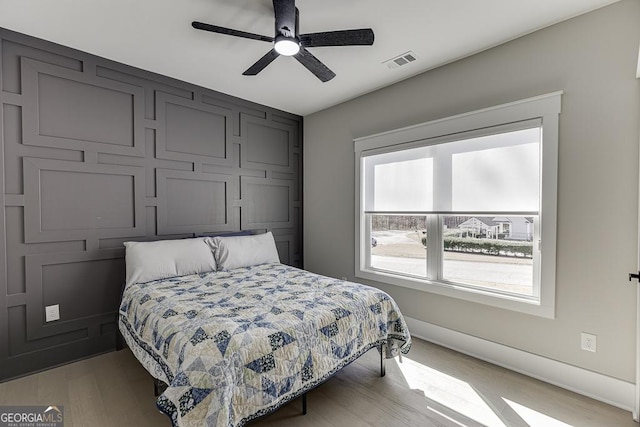 bedroom featuring ceiling fan, visible vents, baseboards, and light wood-style flooring