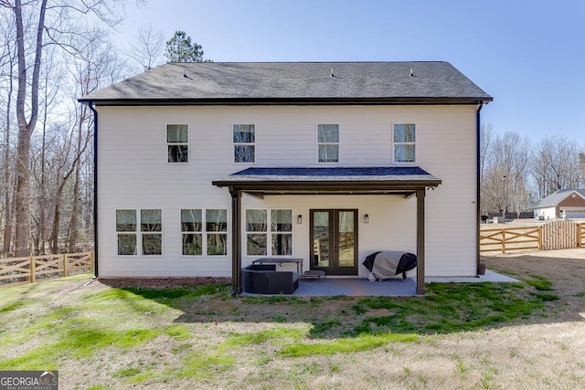 rear view of property featuring a patio area, french doors, a fenced backyard, and roof with shingles