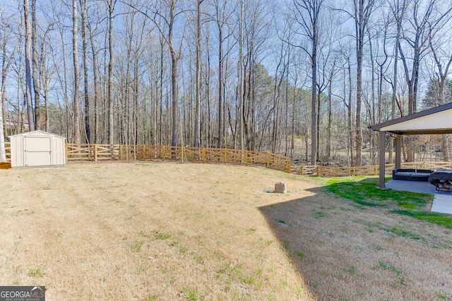 view of yard featuring a view of trees, a storage shed, an outdoor structure, and fence