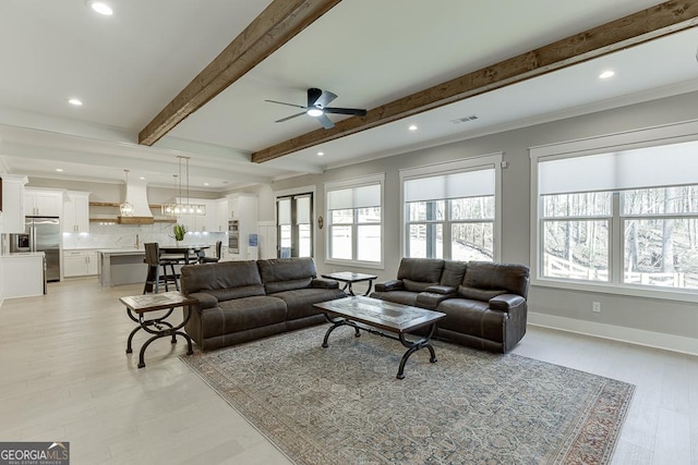 living area with baseboards, visible vents, plenty of natural light, and beam ceiling