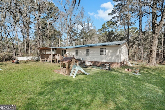 back of property featuring metal roof, a yard, and a wooden deck