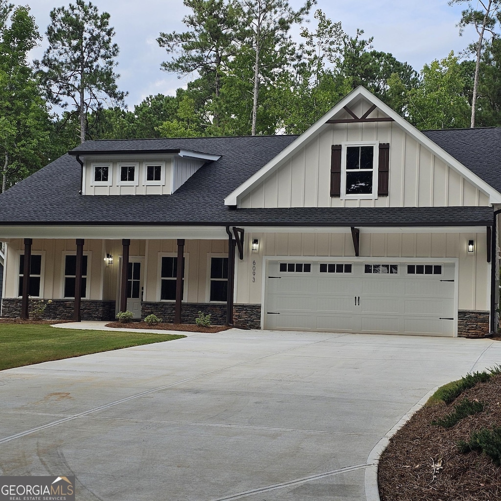 modern farmhouse style home featuring roof with shingles, concrete driveway, board and batten siding, a garage, and stone siding