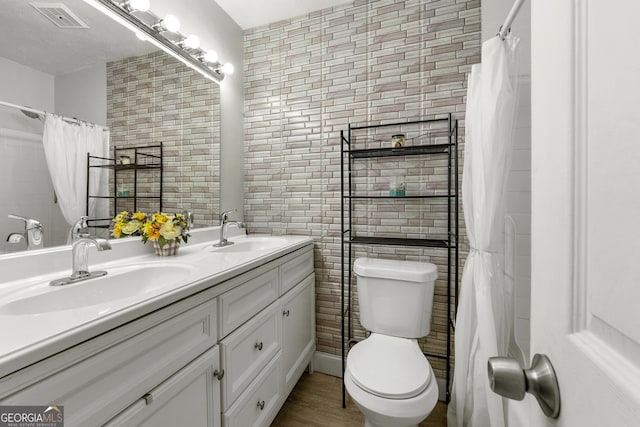 full bathroom featuring toilet, a sink, visible vents, and tile walls