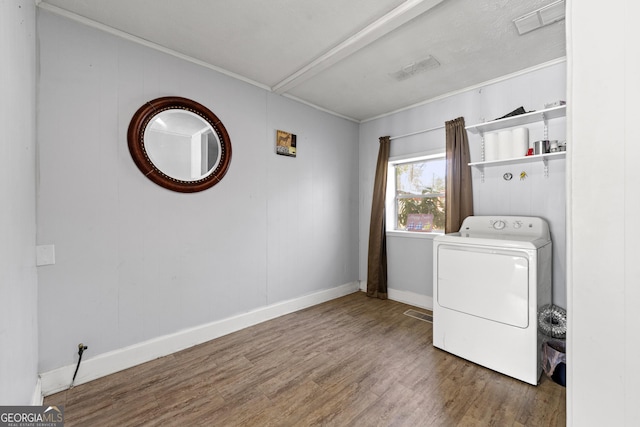 laundry area featuring baseboards, ornamental molding, laundry area, wood finished floors, and washer / dryer