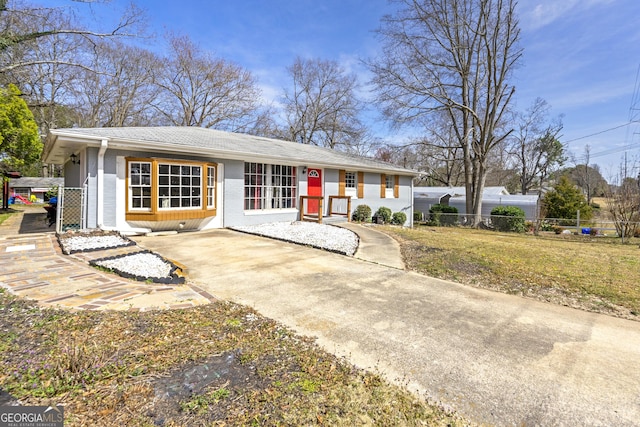 ranch-style house featuring concrete driveway, a front yard, and fence