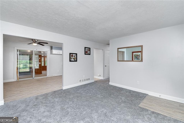 carpeted empty room featuring ceiling fan, a textured ceiling, visible vents, and baseboards