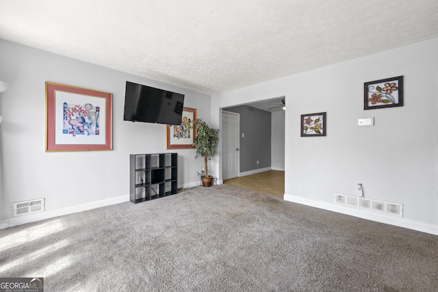 unfurnished living room with baseboards, a ceiling fan, visible vents, and carpet floors