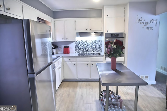 kitchen featuring light wood-style flooring, under cabinet range hood, visible vents, white cabinetry, and appliances with stainless steel finishes