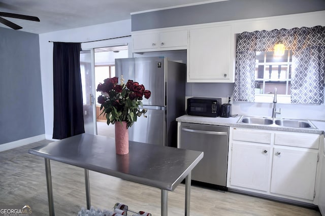 kitchen with stainless steel appliances, a sink, light countertops, and white cabinets