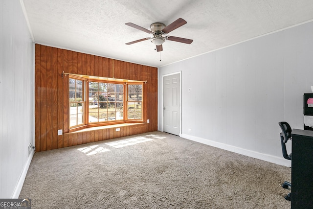 unfurnished office featuring wooden walls, carpet floors, ceiling fan, and a textured ceiling