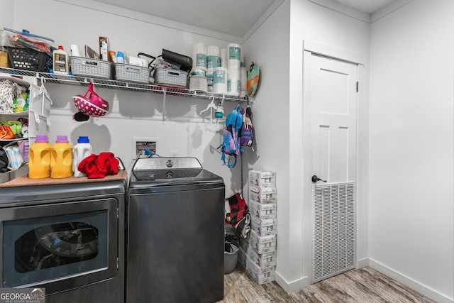 laundry area with laundry area, wood finished floors, washing machine and clothes dryer, and baseboards