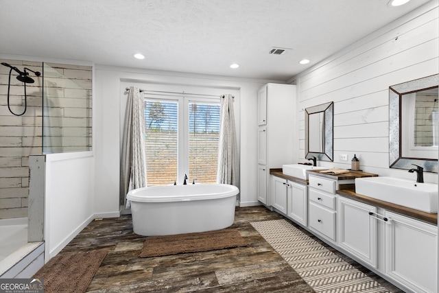 bathroom with a freestanding tub, tiled shower, and a sink