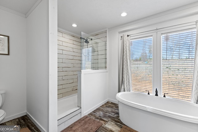 bathroom with a freestanding tub, toilet, wood finished floors, baseboards, and walk in shower