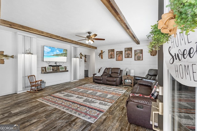 living room with ceiling fan, a fireplace, beamed ceiling, and wood finished floors