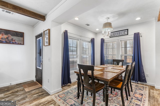 dining area featuring wood finished floors, visible vents, baseboards, beam ceiling, and an inviting chandelier