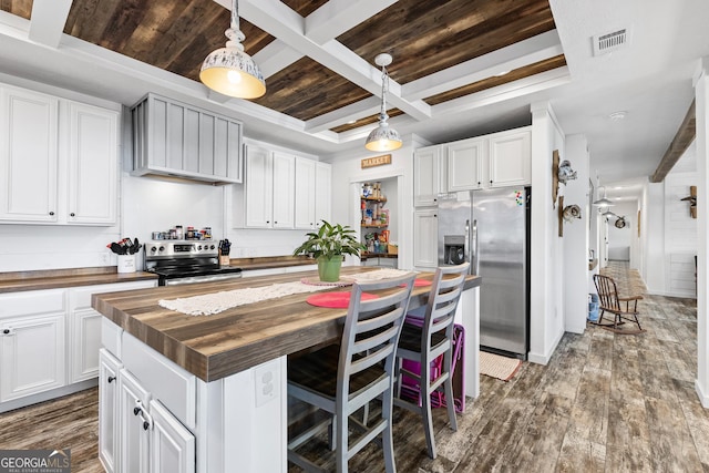 kitchen featuring visible vents, butcher block countertops, dark wood-type flooring, a center island, and stainless steel appliances