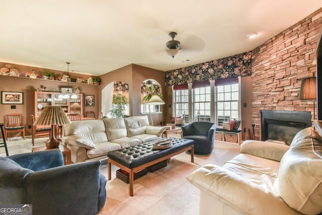 living room with light carpet, ceiling fan, and a stone fireplace