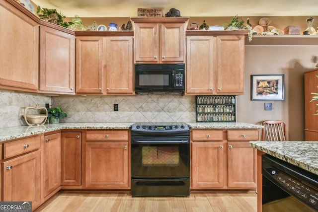 kitchen featuring decorative backsplash, light stone countertops, black appliances, light wood finished floors, and brown cabinetry