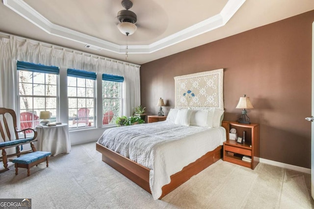 carpeted bedroom with baseboards, visible vents, a raised ceiling, ceiling fan, and crown molding