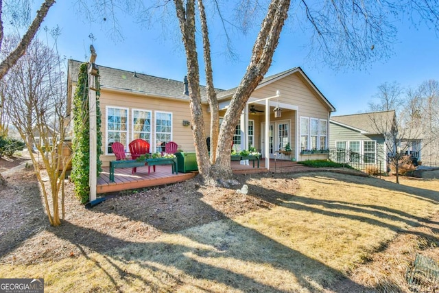 back of property with a lawn, french doors, a ceiling fan, and a wooden deck