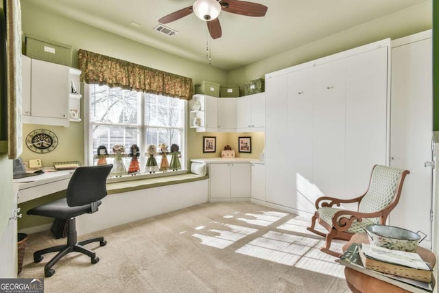 office area featuring a ceiling fan, visible vents, and light colored carpet