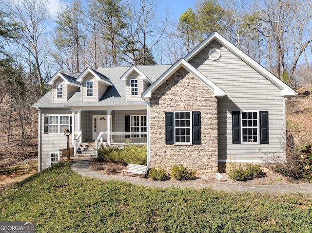 cape cod home featuring stone siding, a front yard, and covered porch