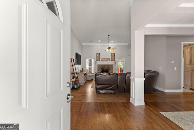 foyer with crown molding, a fireplace, ceiling fan, and wood finished floors