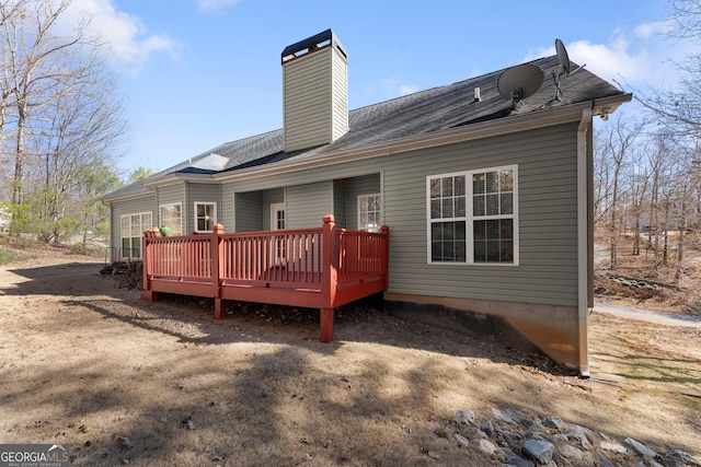 back of property with a deck, a shingled roof, and a chimney