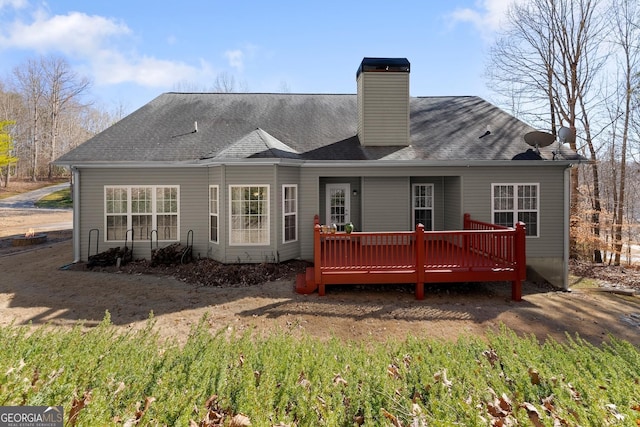 rear view of house with a shingled roof, a chimney, and a wooden deck