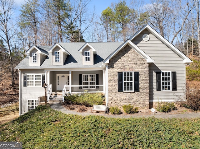 cape cod home featuring stone siding, a porch, and a front yard