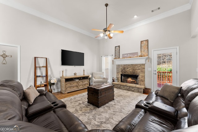 living area featuring a fireplace, visible vents, a ceiling fan, ornamental molding, and light wood-type flooring