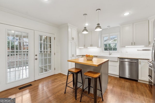 kitchen with visible vents, wooden counters, a sink, french doors, and stainless steel dishwasher