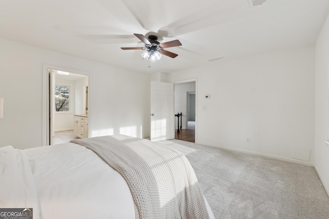 bedroom featuring ensuite bath, a ceiling fan, baseboards, and light carpet