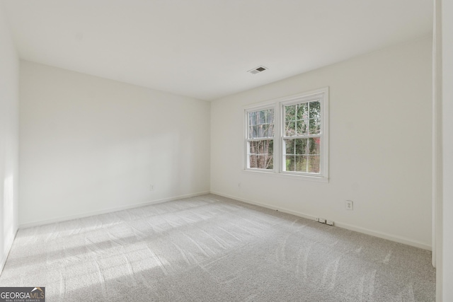 spare room featuring baseboards, visible vents, and light carpet